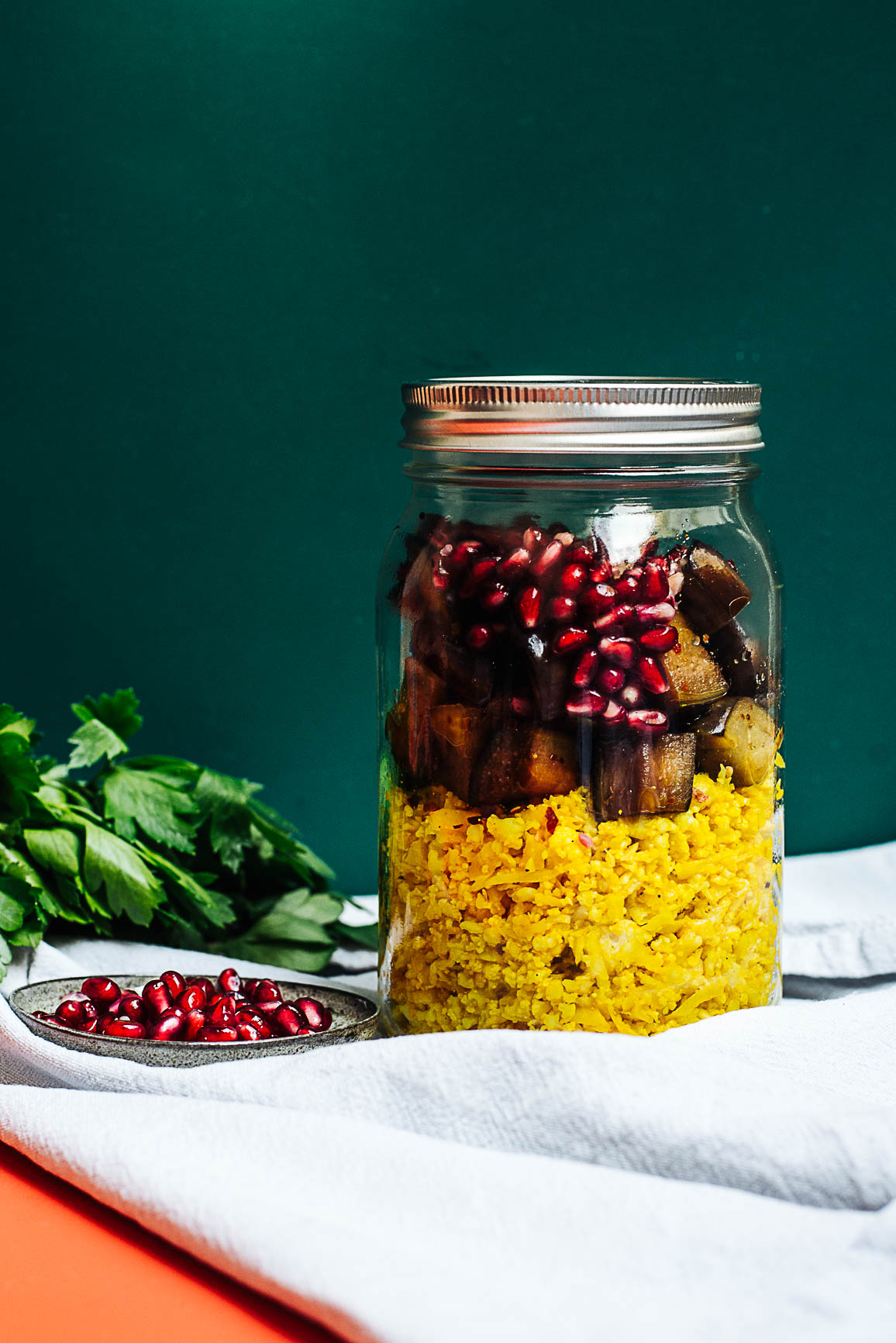 Kurkuma-Blumenkohlreis mit Chili-Auberginen und Granatapfel im Glas